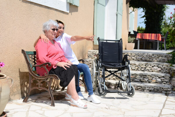 elderly senior woman on a wheelchair with nurse outdoor in nursing home hospital garden